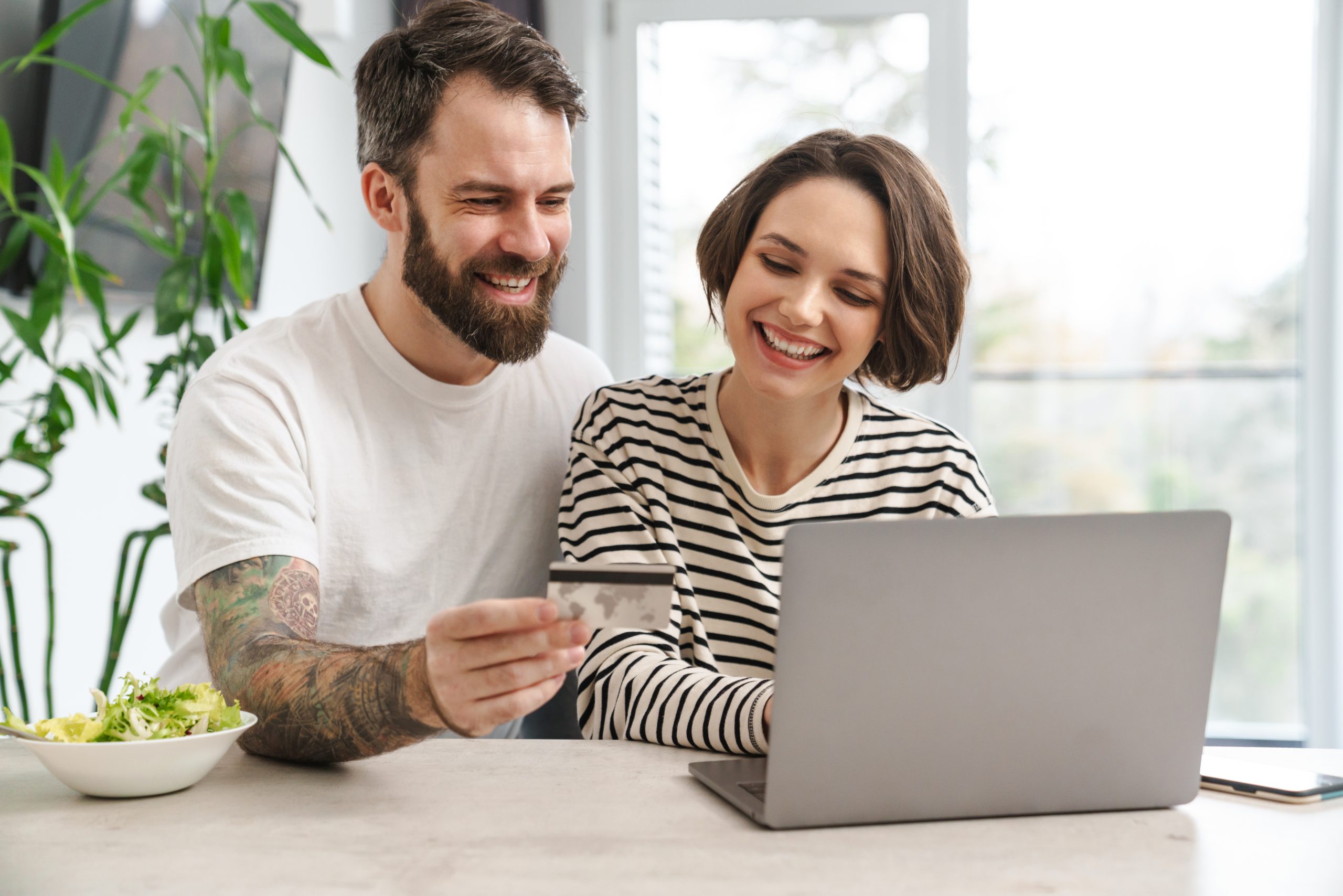 Porträt eines fröhlichen Paares, das mit Laptop online einkauft