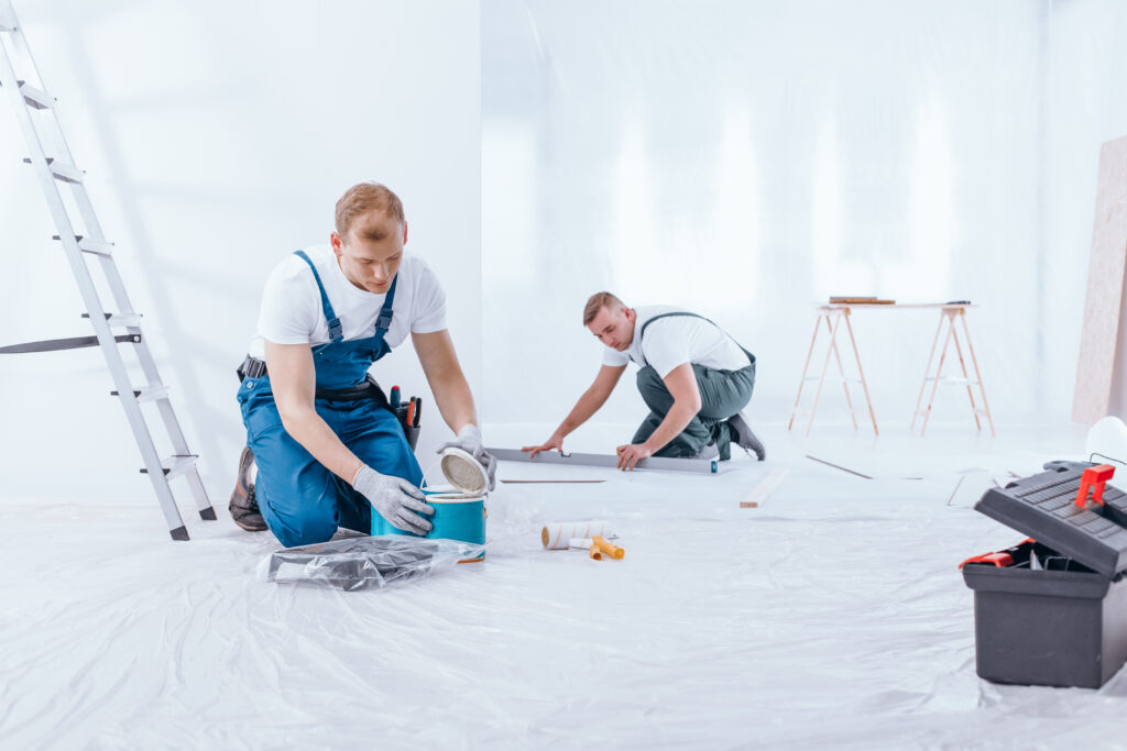 Zwei Männer arbeiten und bedienen sich dazu verschiedener Werkzeuge und Lacke.