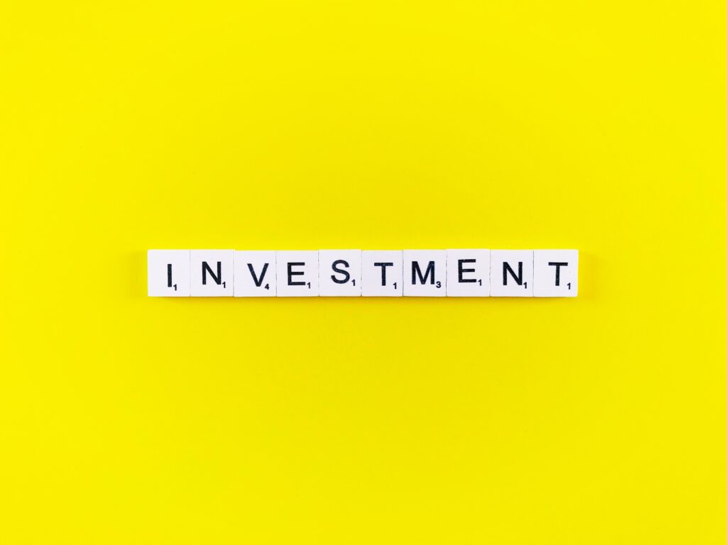 Gelber Hintergrund und die Buchstaben Investment mit jeweils einer kleinen Zahl unter den Buchstaben